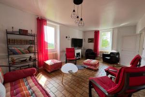 una sala de estar con muebles rojos y cortinas rojas. en Les Gites de Louisette 1886 en Ébreuil