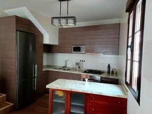Una cocina con gabinetes de madera y un refrigerador negro. en Encantos de Cazorla, en Cazorla