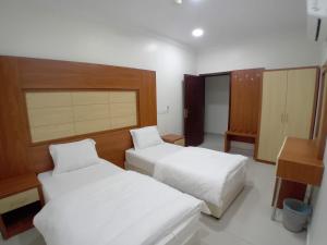 a hotel room with two beds and a desk at فندق 7c in Al Hofuf