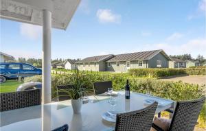 einen Esstisch mit Stühlen und eine Flasche Wein in der Unterkunft Gorgeous Home In Nrre Nebel With Wifi in Lønne Hede
