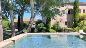 - une piscine en face d'une maison arborée dans l'établissement Le Mas Des Bardes, à Pernes-les-Fontaines