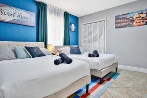 twee bedden in een slaapkamer met blauwe muren bij Vacay Spot Happy Escape 15 Min Beach Massage Shower Prime LOC! 6 blocks away from Bars, Nite Clubs, Res, Shops in Miami