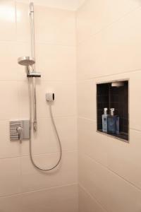 a shower with a hose in a white bathroom at Appartement Burgblick in Harburg
