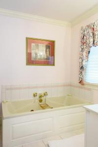 a white bathroom with a tub and a picture on the wall at The Virginia Cliffe Inn in Glen Allen