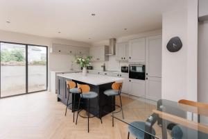 a kitchen with white cabinets and a black island with stools at The Views Cottage in Newcastle +36 photos