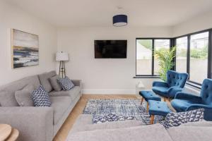 a living room with a couch and two blue chairs at The Views Cottage in Newcastle