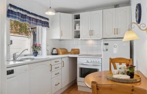 cocina con armarios blancos y mesa de madera en Pet Friendly Home In Rudkbing With Kitchen, en Rudkøbing
