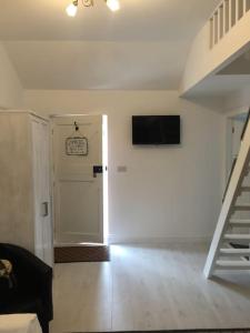 a living room with a staircase and a television on the wall at Hill Head Cottage in Saint Columb Major