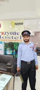 un hombre de uniforme parado junto a una mesa en Frazyone hostel en Nueva Delhi