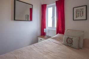 a bedroom with a bed with red curtains and a window at Spring Lake 41, Lapwing Lake Lodge - P in South Cerney