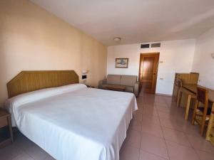 a bedroom with a bed and a chair and a table at AR Roca Esmeralda & SPA Hotel in Calpe