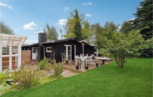 a small black house with a patio and a yard at Cozy Home In Jgerspris With Jacuzzi in Jægerspris