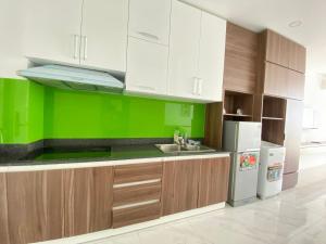 - une cuisine avec des placards blancs et un mur vert dans l'établissement Căn hộ view biển Sea Links MŨI NÉ, à Phan Thiết