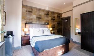 a bedroom with a large bed with a brick wall at Eton House - Self Check-In, Ensuite Rooms & Self-Catering Studios in Yeovil