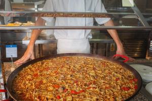 a chef preparing a large pan of food in a kitchen at AR Roca Esmeralda & SPA Hotel in Calpe