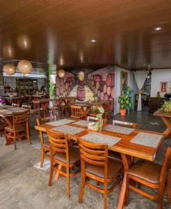 a restaurant with wooden tables and chairs and a mural at Pousada Monte das Serras in Serra de São Bento