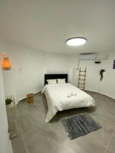 ein Schlafzimmer mit einem Bett mit einer weißen Bettdecke in der Unterkunft דירת אירוח ימית in Bet Scheʼan