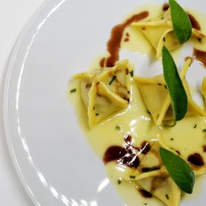 a plate of pasta with sauce and green leaves at Hotel Mirasole International in Gaeta