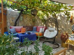 a patio with a couch and chairs under a tree at Apartment Geart in Berat