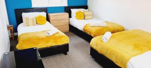 a room with three beds with yellow sheets and yellow blankets at Browning House I Long or Short Stay I Special Rate Available in Derby
