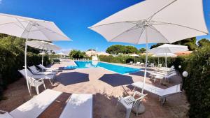 a swimming pool with white umbrellas and chairs and a pool at Villa Teti - Sicilia in Campofelice di Roccella