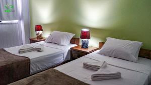 two beds in a room with two lamps and towels at Pousada Green Place in Ribeira Grande