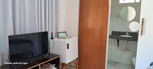 a living room with a flat screen tv and a bathroom at Pousada Jardim da Lagoa-BA in Bom Jesus da Lapa