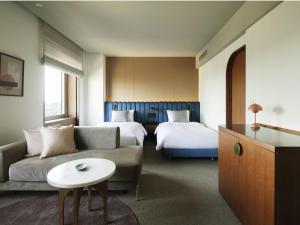 The Mark Grand Hotel في سايتاما: غرفة في الفندق مع أريكة وسرير