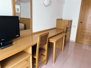 a room with a desk with a television and chairs at AR Roca Esmeralda & SPA Hotel in Calpe