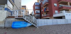 ein blaues Boot auf dem Sand neben einem Gebäude in der Unterkunft Tavernes de Valldigna Chez Svetlana in El Brosquil