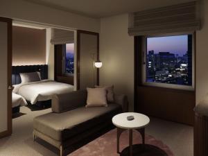 a hotel room with a couch and a bed and a window at The Mark Grand Hotel in Saitama