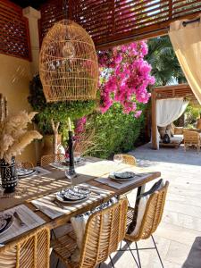 einen Holztisch mit Stühlen und rosa Blumen in der Unterkunft Villa rouge in Marrakesch
