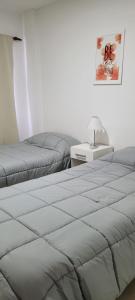 1 dormitorio con 2 camas y mesa con lámpara en Apartamento en el centro de Banfield en Banfield