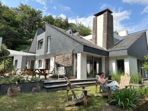 a woman sitting on a bench in front of a house at La Maison de l'Orbière in Forcé