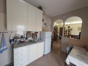 a kitchen with white cabinets and a table and a person at Appartamento Vinovo Centro in Vinovo
