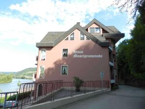 ein rosafarbenes Gebäude mit einem Zaun neben einem Fluss in der Unterkunft Ferienwohnung Lastro in Cochem