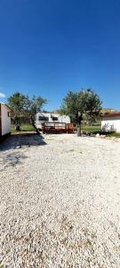 un grande campo di ghiaia con una casa e due alberi di FeudoMallav nice roulotte b&b Noto a Noto