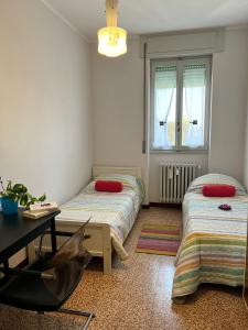 Cette chambre comprend deux lits, un bureau et une table. dans l'établissement Bnbook Trilo Malpensa, à Cardano al Campo