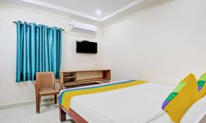 1 dormitorio con 1 cama, TV y silla en vardhan @stay inn, en Tirupati
