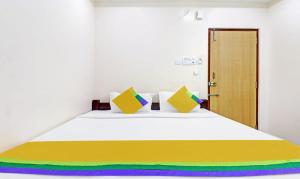 1 dormitorio con 1 cama blanca grande con almohadas coloridas en vardhan @stay inn, en Tirupati