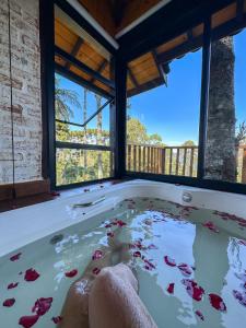 a jacuzzi tub in a room with windows at Chalés Descanso na Serra in Monte Verde