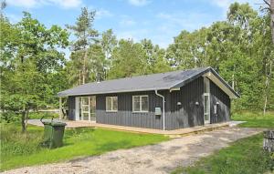 una pequeña cabaña negra en medio de un campo en 3 Bedroom Beautiful Home In Grenaa, en Grenå