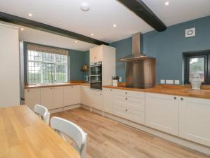 a kitchen with white cabinets and a wooden table at Byways in Malvern Link