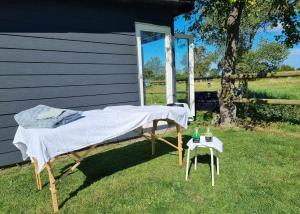 a bed and a table in the grass next to a house at Falsterly Glamping in Horbelöv