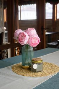 un jarrón verde con flores rosas sobre una mesa en Meteor Family Hotel, en Chepelare