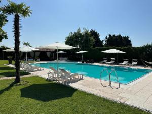 einen Pool mit Stühlen und Sonnenschirmen in der Unterkunft Relais Corte Bercelli in Valeggio sul Mincio