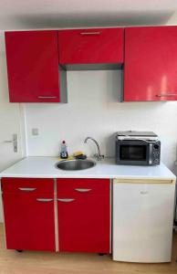 a red kitchen with a sink and a microwave at Appartement in MG City Self- Check-in in Mönchengladbach +6 photos