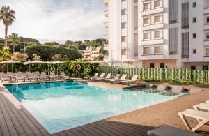 a swimming pool with lounge chairs and a building at ALEGRIA Fenals Mar in Lloret de Mar