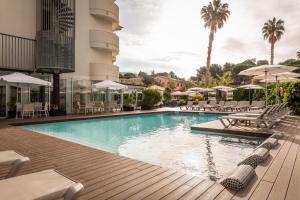 une piscine dans un hôtel avec des chaises et des parasols dans l'établissement ALEGRIA Fenals Mar, à Lloret de Mar