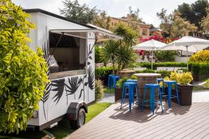 a food trailer with tables and stools in a garden at ALEGRIA Fenals Mar in Lloret de Mar